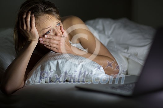Pretty young woman watching something awful/sad on her laptop in bed Pretty young woman watching something awful/sad on her laptop in bed