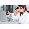 Two young female researchers carrying out experiments in a lab (shallow DOF; color toned image)