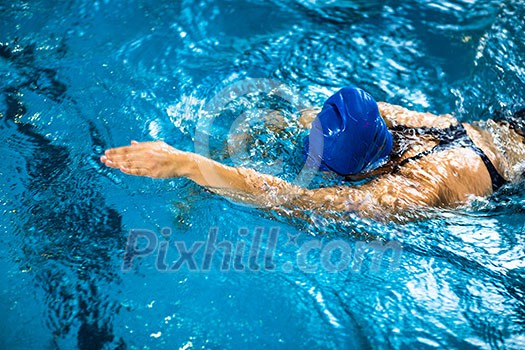 Female swimmer in an indoor swimming pool - doing crawl (shallow DOF) Female swimmer in an indoor swimming pool - doing crawl (shallow DOF)