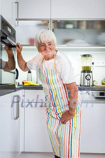 Senior woman cooking in the kitchen - eating and cooking healthy for her family; putting some potates in the oven, enjoying active retirement (shallow DOF; color toned image) Senior woman cooking in the kitchen - eating and cooking healthy for her family; putting some potates in the oven, enjoying active retirement (shallow DOF; color toned image)