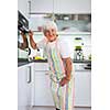 Senior woman cooking in the kitchen - eating and cooking healthy for her family; putting some potates in the oven, enjoying active retirement (shallow DOF; color toned image)