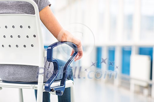 Female patient, sitting in a wheelchair for patients feeling not well enough to stand, waiting to be taken care of in a modern hospital (shallow DOF; color toned image) Female patient, sitting in a wheelchair for patients feeling not well enough to stand, waiting to be taken care of in a modern hospital (shallow DOF; color toned image)