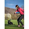 Young woman throwing freisbee to her black dog outdoors (shallow DOF, sharp focus
