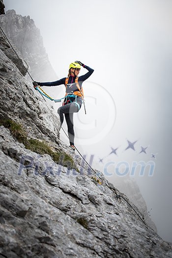 Pretty, female climber on a via ferrata - climbing on a rock in Swiss Alps Pretty, female climber on a via ferrata - climbing on a rock in Swiss Alps