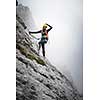 Pretty, female climber on a via ferrata - climbing on a rock in Swiss Alps