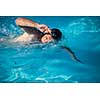 Male swimmer swimming crawl in an outdoor pool - keeping fit