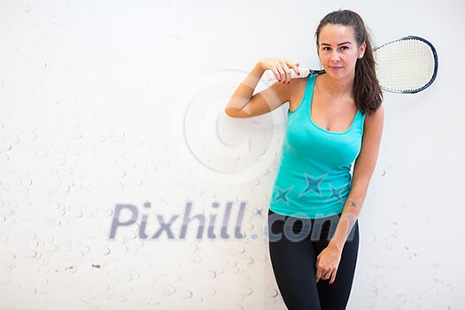 Cute young woman with a racket leaning against a wall in a squash court, ready for the game Cute young woman with a racket leaning against a wall in a squash court, ready for the game