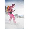 Pretty, young woman snowshoeing in high mountains, enjoying splendid winter weather with abundance of snow