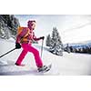 Pretty, young woman snowshoeing in high mountains, enjoying splendid winter weather with abundance of snow