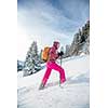 Pretty, young woman snowshoeing in high mountains, enjoying splendid winter weather with abundance of snow