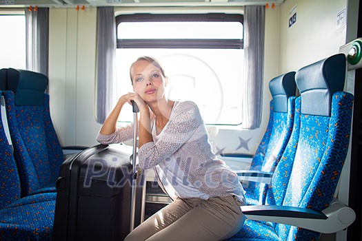 Pretty young woman traveling on a train with her big trunk (color toned image) Pretty young woman traveling on a train with her big trunk (color toned image)
