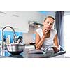Pretty, young woman in her modern, clean and bright kitchen, fixing lunch (color toned imagey; shallow DOF)