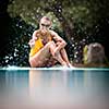 Young Beautiful Suntanned Woman wearing sunglasses relaxing next to a Swimming Pool  on a lovely Summer Day