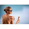 Suncream Concept. Pretty, young woman in a swimsuit is applying sunscreen trying to protect the skin from the harmful effects of sunlight she loves