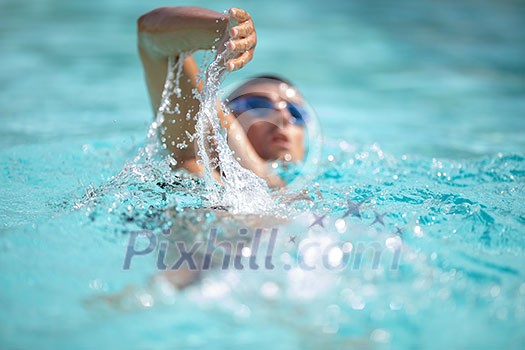 Man swimmer swimming crawl in a blue water pool. Portrait of an athletic young male triathlete swimming crawl wearing swimming goggles. Triathlete training for triathlon. Man swimmer swimming crawl in a blue water pool. Portrait of an athletic young male triathlete swimming crawl wearing swimming goggles. Triathlete training for triathlon.