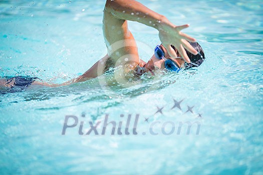 Man swimmer swimming crawl in a blue water pool. Portrait of an athletic young male triathlete swimming crawl wearing swimming goggles. Triathlete training for triathlon. Man swimmer swimming crawl in a blue water pool. Portrait of an athletic young male triathlete swimming crawl wearing swimming goggles. Triathlete training for triathlon.