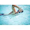 Man swimmer swimming crawl in a blue water  pool. Portrait of an athletic young male triathlete swimming crawl wearing swimming goggles. Triathlete training for triathlon.