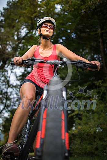 Pretty, young woman riding her mountain bike on a forest path. Enjoying active leisure time outdoors. Pretty, young woman riding her mountain bike on a forest path. Enjoying active leisure time outdoors.
