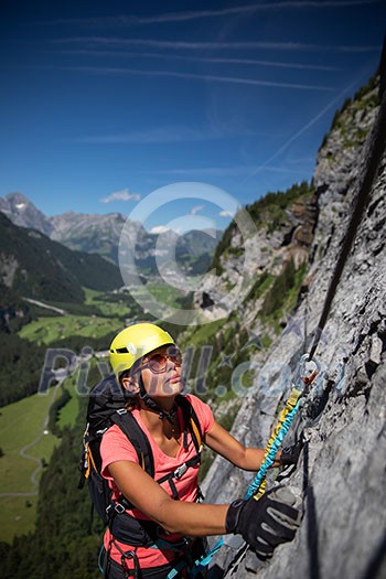 Pretty, female climber on a via ferrata - climbing on a rock in Swiss Alps Pretty, female climber on a via ferrata - climbing on a rock in Swiss Alps