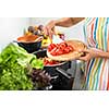 Young woman cutting vegetables in her modern kitchen - fixing a salad