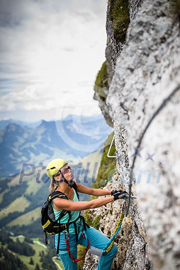 Pretty, female climber on a via ferrata - climbing on a rock in Swiss Alps Pretty, female climber on a via ferrata - climbing on a rock in Swiss Alps