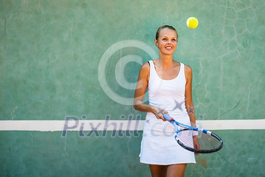 Portrait of a pretty, young, female tennis player in front of a training wall on a tennis court Portrait of a pretty, young, female tennis player in front of a training wall on a tennis court