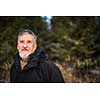 Portrait of a senior man, outdoor on a snowy forest path. Enjoying the crisp fresh air, watching the Sun go down.
