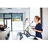 Pretty, young business woman giving a presentation in a conference/meeting setting (shallow DOF; color toned image)