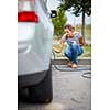 Young woman checking the car tyre pressure - inflating it