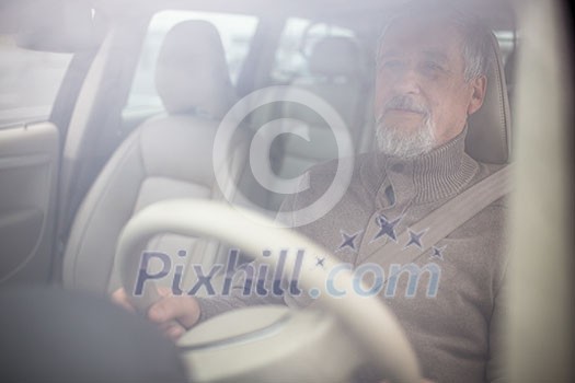 Senior man driving his modern car, going in reverse, watching out not to hit anything or anyone (color toned image; shallow DOF) Senior man driving his modern car, going in reverse, watching out not to hit anything or anyone (color toned image; shallow DOF)