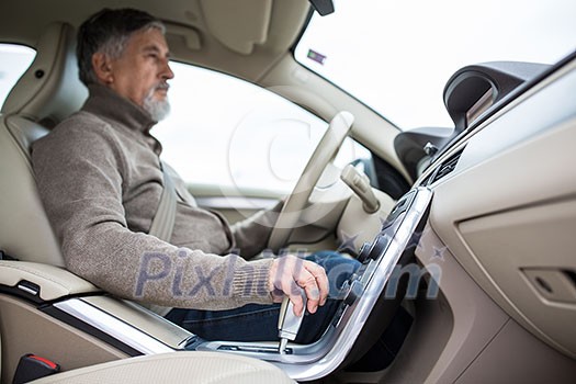 Senior man driving his modern car, going in reverse, watching out not to hit anything or anyone (color toned image; shallow DOF) Senior man driving his modern car, going in reverse, watching out not to hit anything or anyone (color toned image; shallow DOF)
