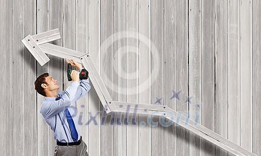 Young businessman using drill to fix growing arrow Young businessman using drill to fix growing arrow