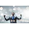 Young handsome businessman with hands up celebrating success