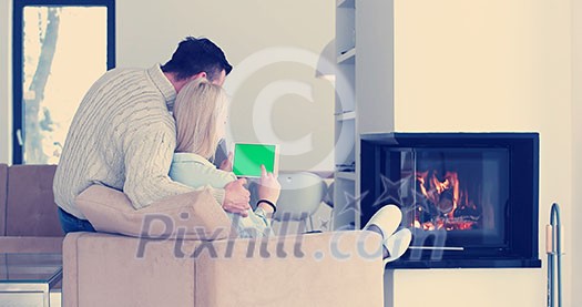 Young couple relaxing at luxurious home with tablet computers reading in the living room on the sofa couch. Young couple relaxing at luxurious home with tablet computers reading in the living room on the sofa couch.