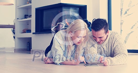 Young Couple sitting on the floor and using interent on digital tablet Young Couple sitting on the floor and using interent on digital tablet