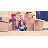 people, moving new place and repair concept   happy beautiful  young woman with many cardboard boxes sitting on floor with Cup at home