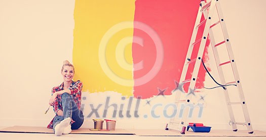 Portrait of a beautiful young female painter sitting on floor near wall after painting. Portrait of a beautiful young female painter sitting on floor near wall after painting.