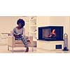 Young beautiful african american woman sitting in front of fireplace at home on a cold autumn day and reading book