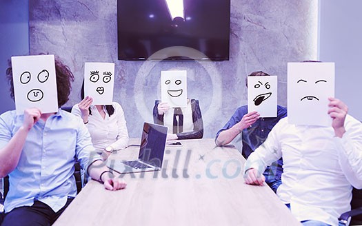 Portrait of a young business team holding a white paper over their face in the startup office Portrait of a young business team holding a white paper over their face in the startup office