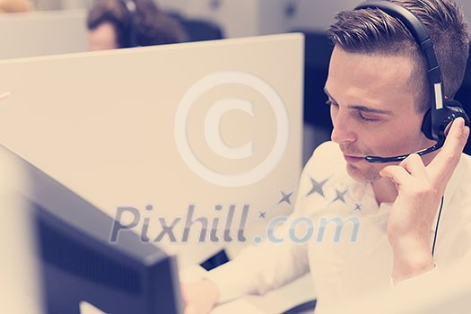 young smiling male call centre operator doing his job with a headset young smiling male call centre operator doing his job with a headset