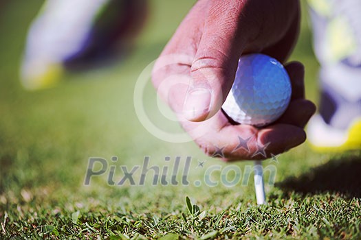 golf player placing ball on tee. beautiful sunrise on golf course landscape in background golf player placing ball on tee. beautiful sunrise on golf course landscape in background