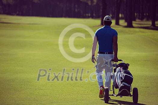 handsome middle eastern golf playerwalking with wheel bag at course on beautiful sunny day handsome middle eastern golf playerwalking with wheel bag at course on beautiful sunny day