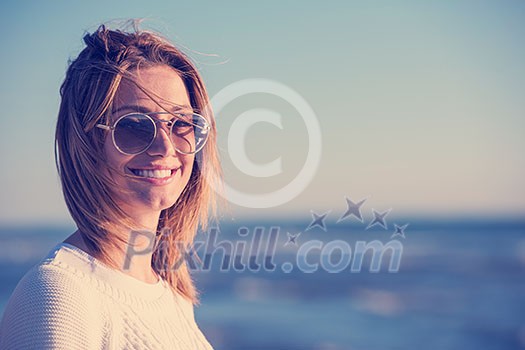 Young woman on the beach. The girl enjoying the warm autumn day. Portrait of beautiful girl near the water Young woman on the beach. The girl enjoying the warm autumn day. Portrait of beautiful girl near the water