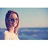 Young woman on the beach. The girl enjoying the warm autumn day. Portrait of beautiful girl near the water