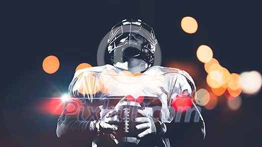 portrait of confident American football player holding ball while standing on field at night portrait of confident American football player holding ball while standing on field at night