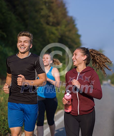 group of young people jogging on country road runners running on open road on a summer day group of young people jogging on country road runners running on open road on a summer day