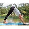 healthy woman relaxing while meditating and doing yoga exercise in the beautiful nature on the bank of the river