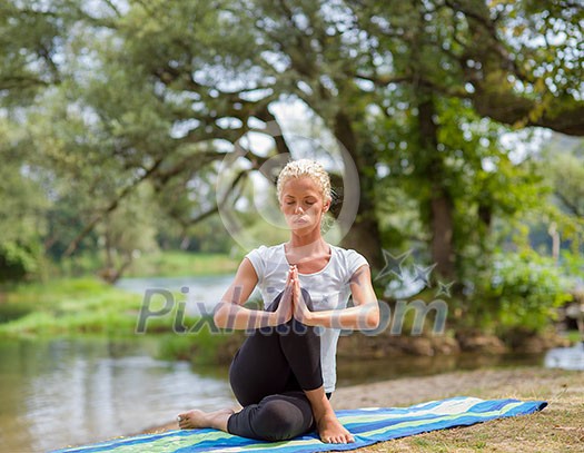 healthy woman relaxing while meditating and doing yoga exercise in the beautiful nature on the bank of the river