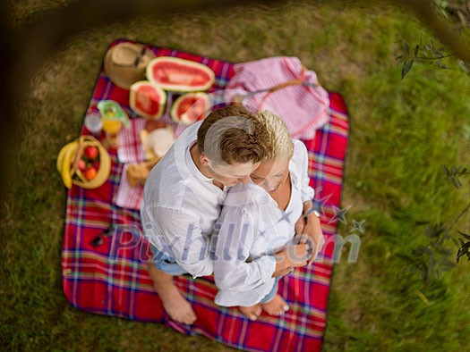 Couple in love enjoying picnic time drink and food in beautiful nature on the river bank top view Couple in love enjoying picnic time drink and food in beautiful nature on the river bank top view