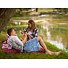 Couple in love enjoying picnic time drink and food in beautiful nature on the river bank